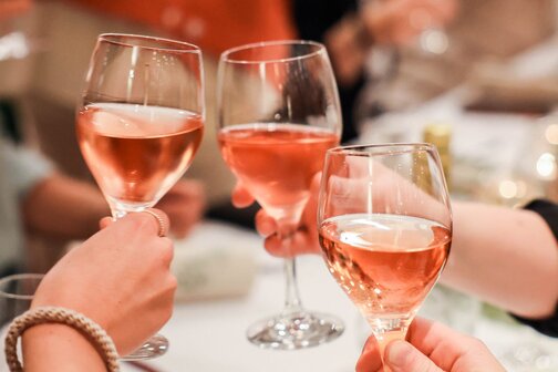 Drei Personen stoßen mit Rose gemeinsam an