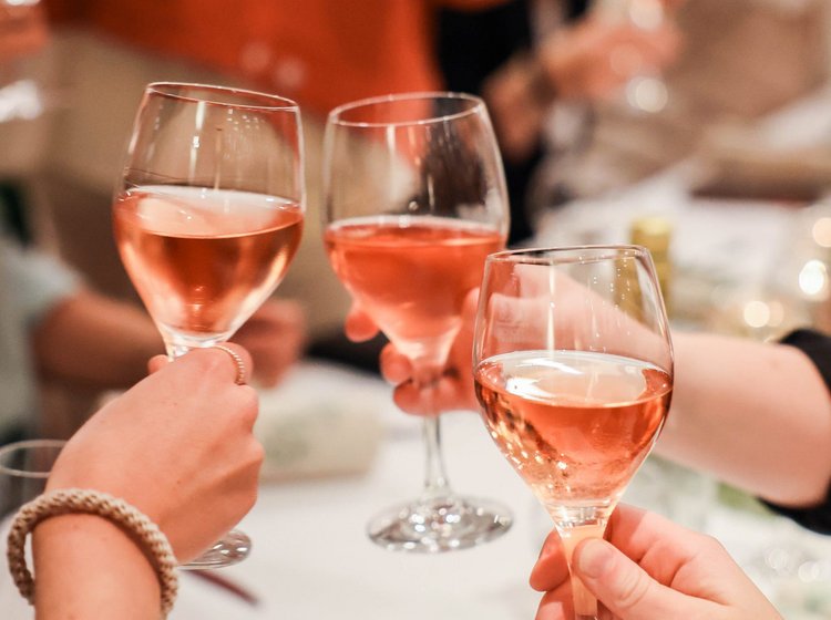 Drei Personen stoßen mit Rose gemeinsam an